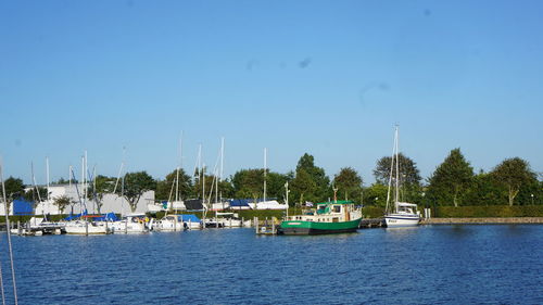 Boats moored in marina against blue sky