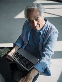 Businessman using laptop while sitting on floor at office