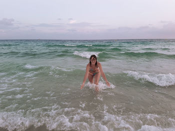 Full length of young woman on beach against sky