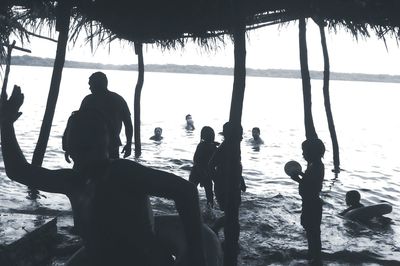 Silhouette people playing on beach against sky