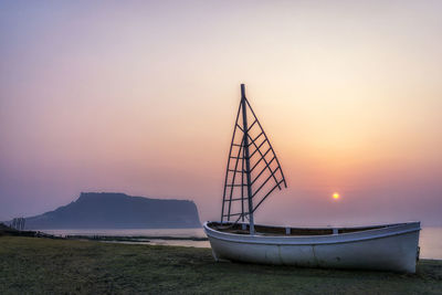 Boat moored in sea against sky during sunset