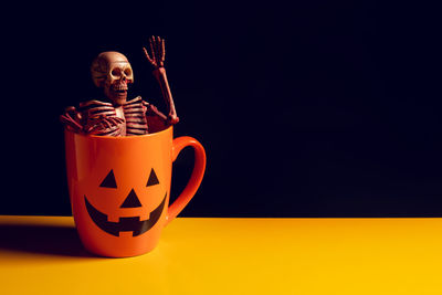 Coffee cup on table against orange background