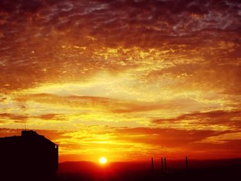 Silhouette building against dramatic sky during sunset