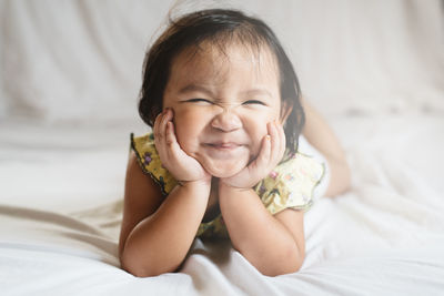 Portrait of cute baby girl lying on bed at home