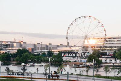 Ferris wheel by river against clear sky