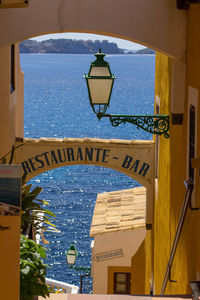 Illuminated text by sea against blue sky