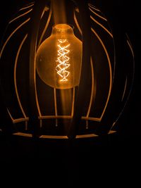 Close-up of illuminated light bulb against black background