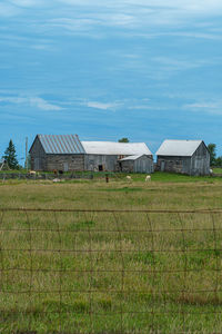 House on field by houses against sky