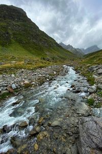 Scenic view of river stream amidst mountains against sky