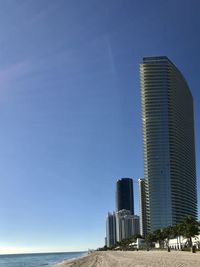 Modern building by sea against clear blue sky