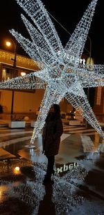 Rear view of woman on illuminated fountain at night