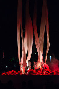 Reflection of people in illuminated traditional clothing at night