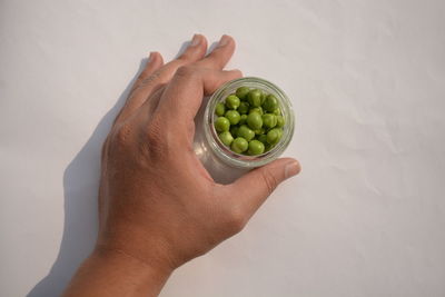 Close-up of hand holding fruit against white background