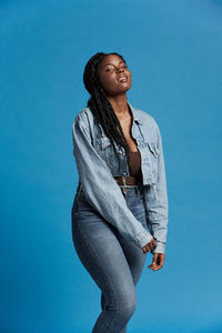 Low angle view of young woman standing against blue sky