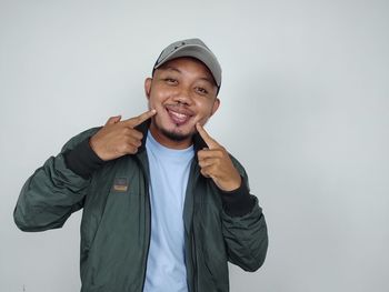 Portrait of young man standing against white background