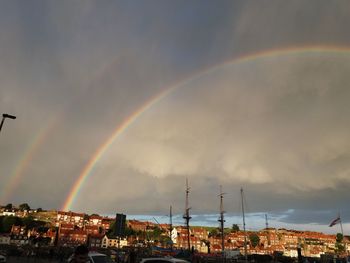 Rainbow over buildings in city against sky