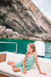 Woman sitting on rock by sea