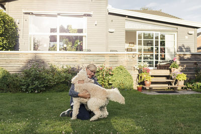 Mature woman embracing dog at front yard