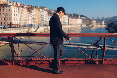 Man standing by railing against sky
