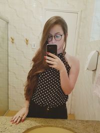 Young woman taking selfie in bathroom