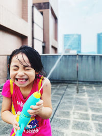 Portrait of smiling young woman playing water in city