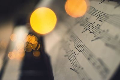 Close-up of illuminated lighting equipment and sheet music