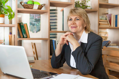 Young woman using phone while sitting on table