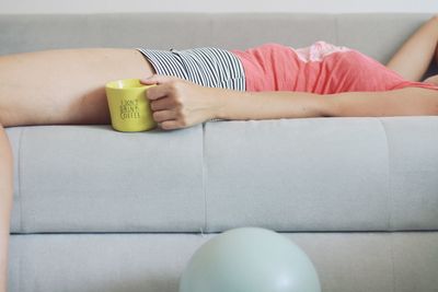 Midsection of woman holding sofa at home