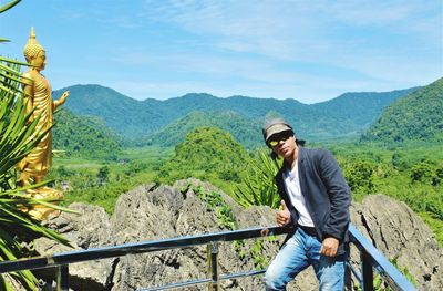 Mature man wearing sunglasses standing against landscape during sunny day