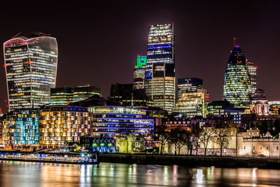 Thames river against illuminated buildings at night