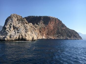 Rock formations by sea against clear blue sky