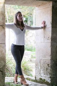 Young woman standing against wall