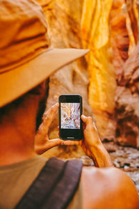 Young man wearing hat taking picture of slot canyons in kanarra falls