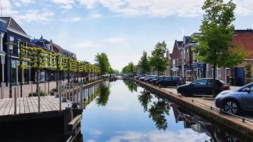 Reflection of trees in canal against sky