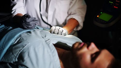 Midsection of doctor examining male patient in hospital