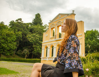 Low angle view of young woman standing against trees