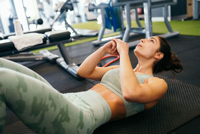 Athlete exercising while lying down on mat at gym