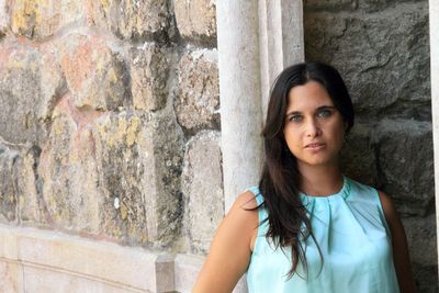 Portrait of young woman standing against wall