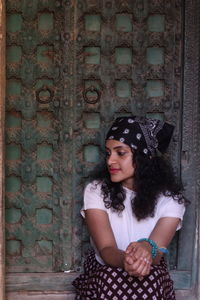 Portrait of a young woman standing against wall