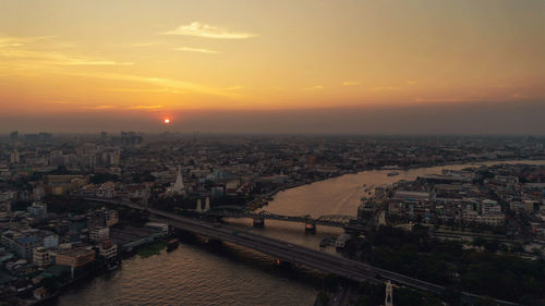 High angle view of river amidst buildings in city during sunset