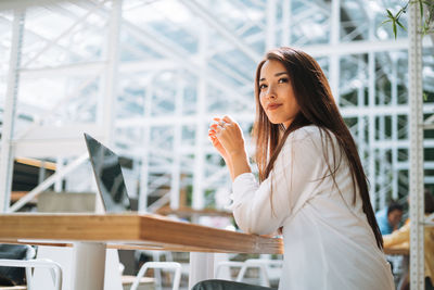 Young asian woman student freelancer with long hair working on laptop in street cafe