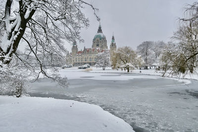 New town hall of hannover covered in snow during winter with the frozen maschteich in the foreground