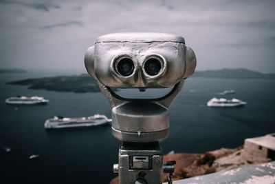 Close-up of coin-operated binoculars by sea against sky