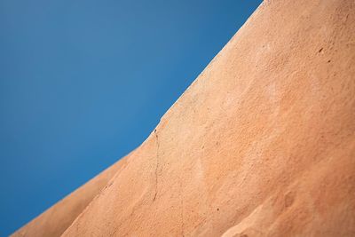 Low angle view of sand against clear blue sky