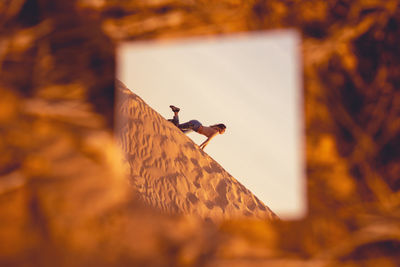 Reflection of woman posing on sand in mirror