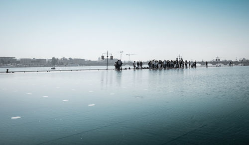 People enjoying at sea against clear sky