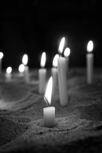 Close-up of candles in sand at night