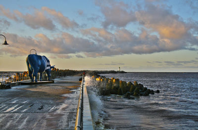 Scenic view of waves crashing on promenade against sky