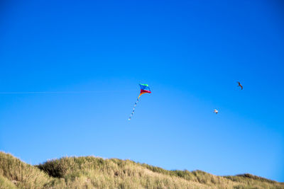 Low angle view of kite flying against clear blue sky