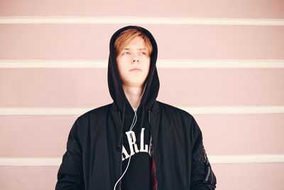 Portrait of young man standing against wall